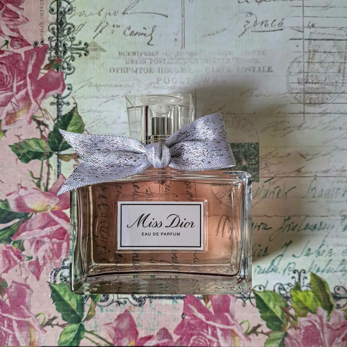 Miss Dior Eau de Parfum bottle placed against a vintage floral background.