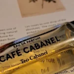 Teo Cabanel Café Cabanel perfume bottle with golden liquid and black cap on a plain background.