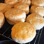 A warm homemade biscuit with melted butter and golden honey drizzled on top.