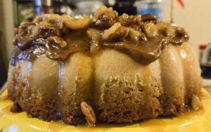A tight close-up shot of a Bananas Foster Flan Cake, focusing on the thick, glossy caramel and rum sauce dripping down the side. Chunks of banana and toasted pecans are visible in the topping.
