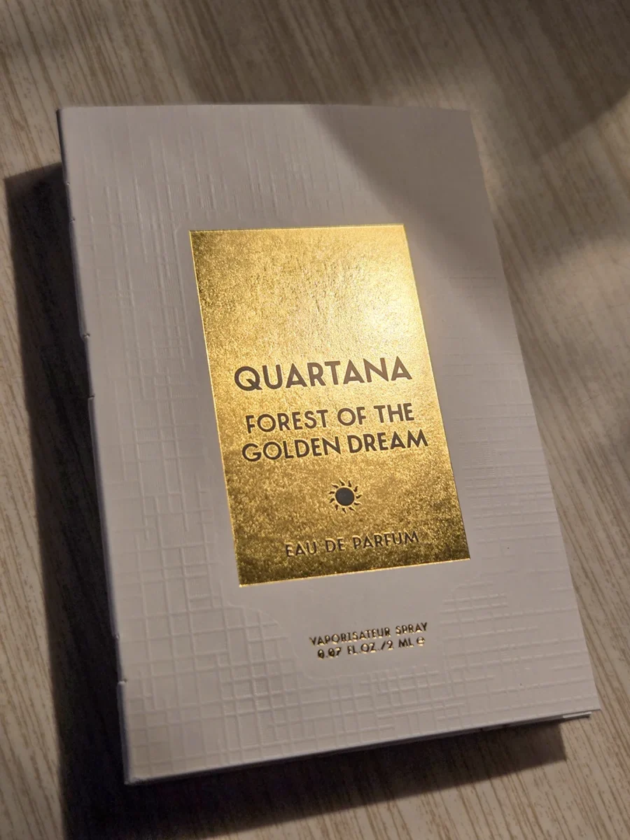 The textured, light grey sample cardholder for Quartana Forest of the Golden Dream, featuring a metallic gold label with black text.