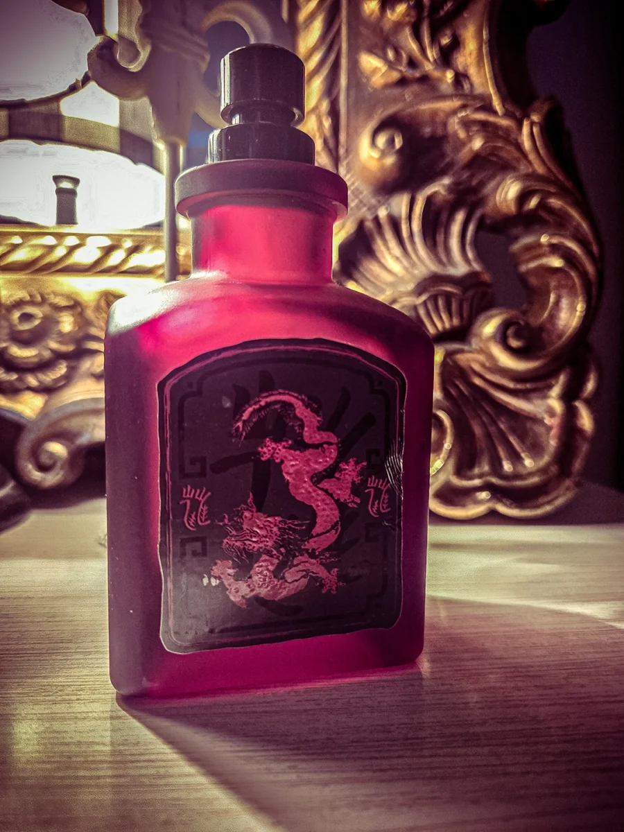 A frosted matte red Lucky Number 6 perfume bottle with a black and pink dragon label, set against a warm, decorative background.