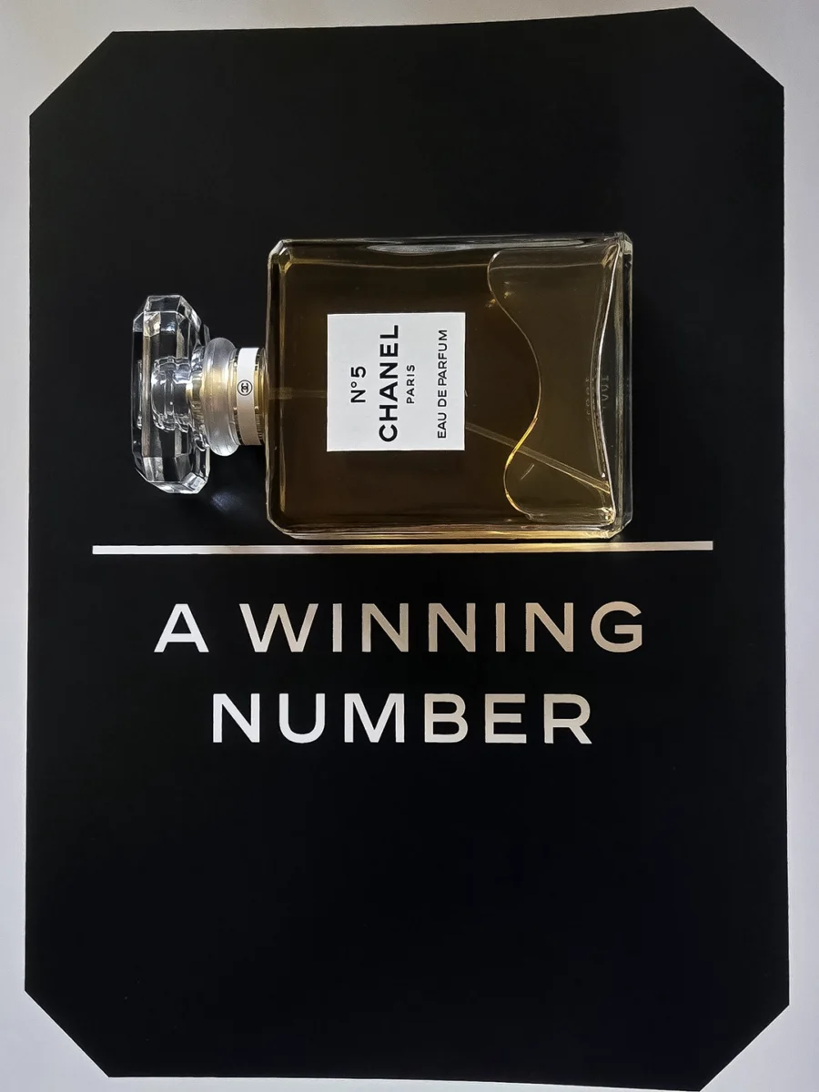 Chanel N°5 Eau de Parfum bottle resting on open pages of the Abrams book, "The Story of Chanel N°5."