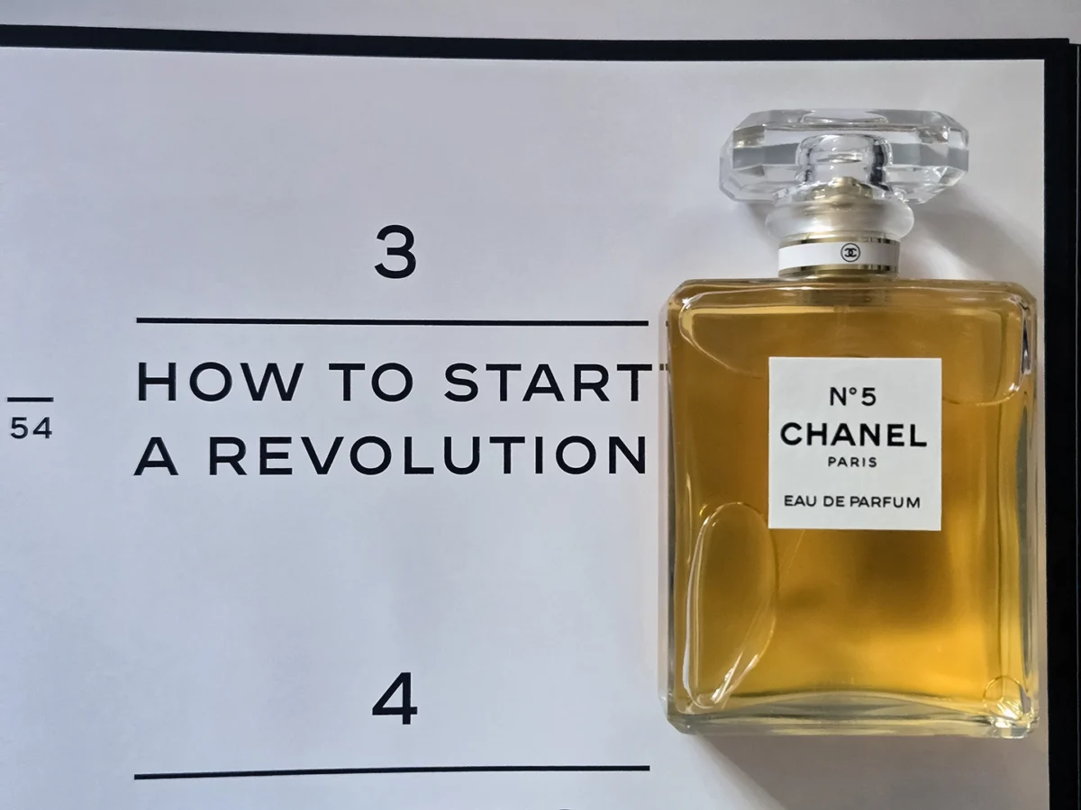 Chanel N°5 Eau de Parfum bottle resting on open pages of the Abrams book, "The Story of Chanel N°5."