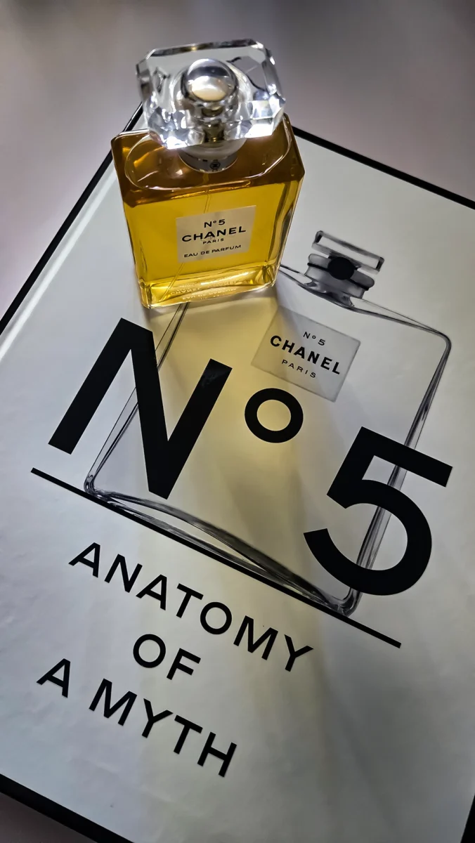 Chanel N°5 Eau de Parfum bottle resting on open pages of the Abrams book, "The Story of Chanel N°5."