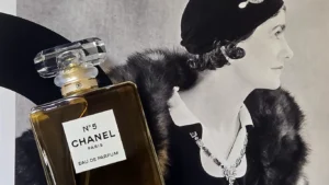 A bottle of Chanel N°5 Eau de Parfum placed over a classic black-and-white portrait of Gabrielle "Coco" Chanel in a fur-trimmed coat from the Pauline Dreyfus book set.