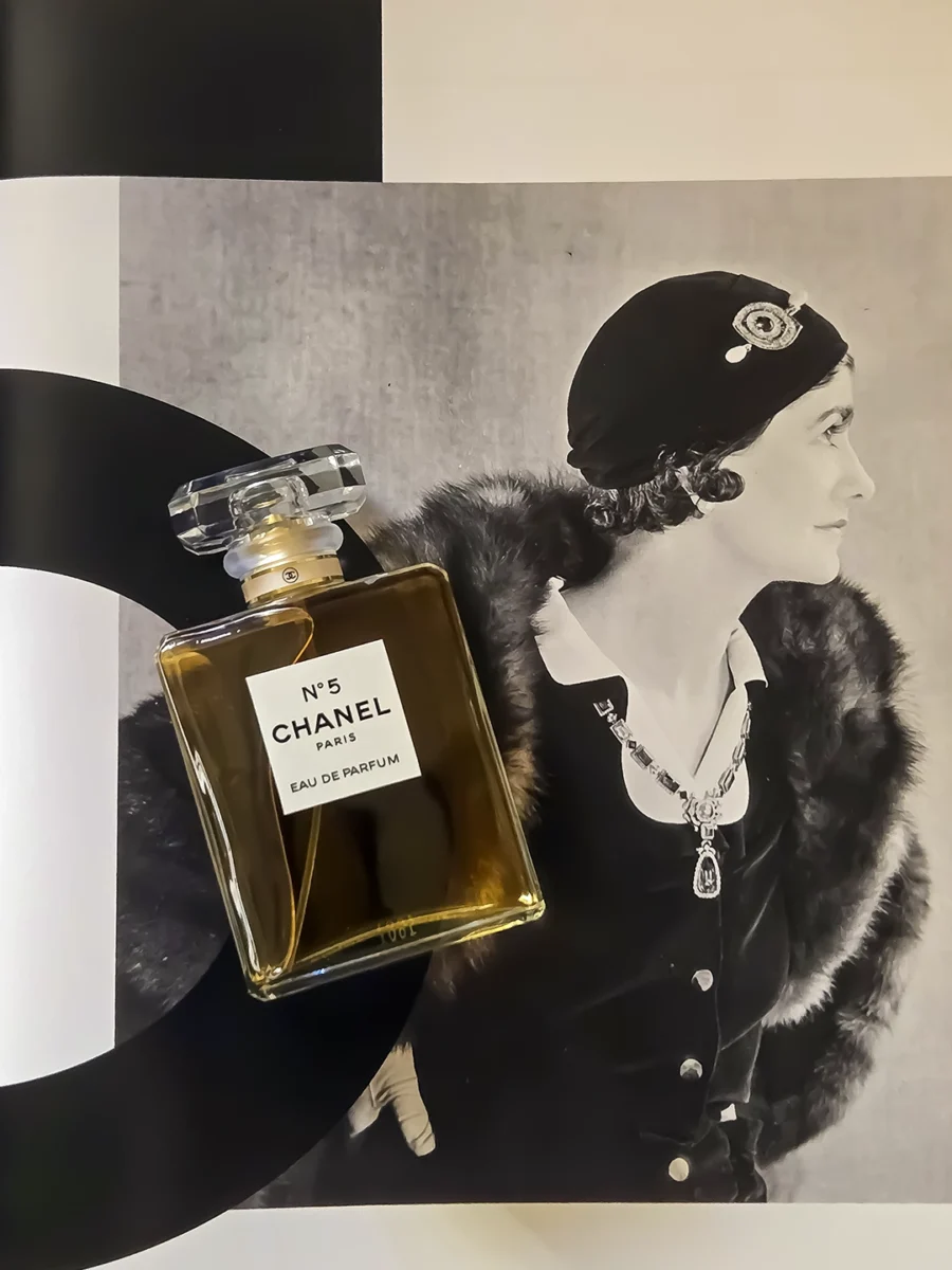 Chanel N°5 Eau de Parfum bottle resting on open pages of the Abrams book, "The Story of Chanel N°5."