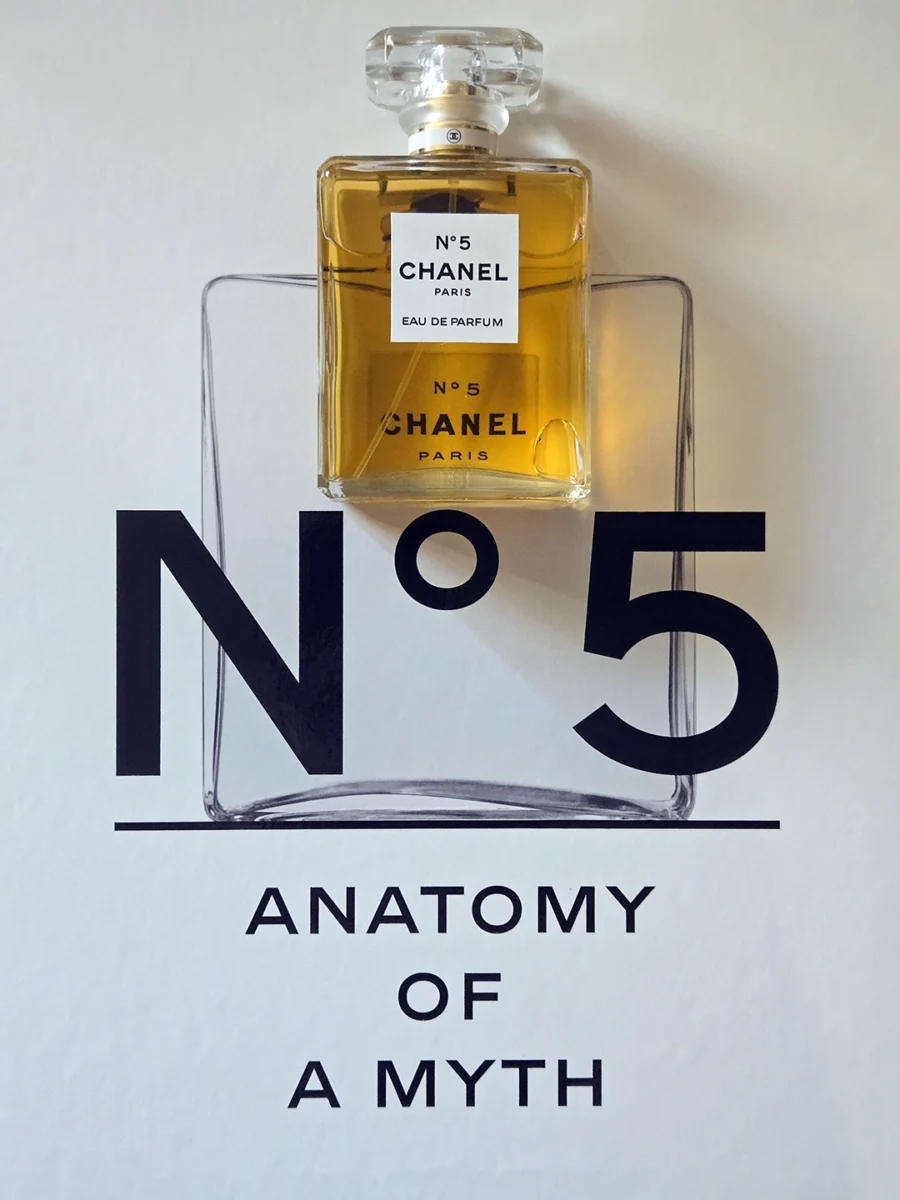 Chanel N°5 Eau de Parfum bottle resting on open pages of the Abrams book, "The Story of Chanel N°5."