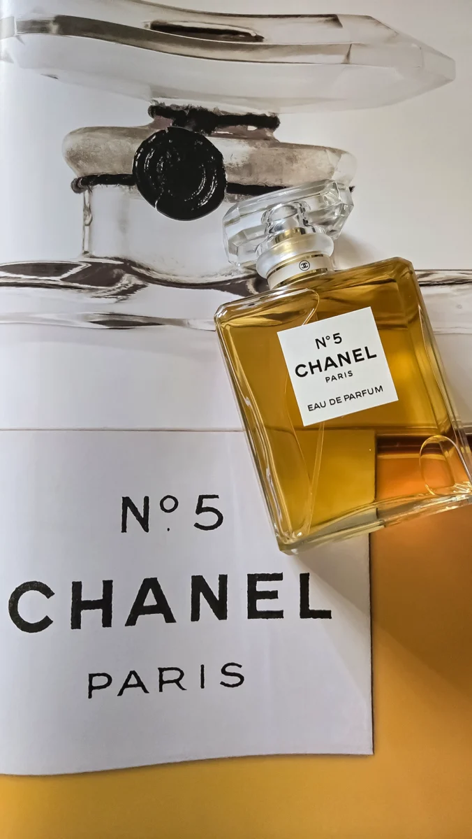 Chanel N°5 Eau de Parfum bottle resting on open pages of the Abrams book, "The Story of Chanel N°5."