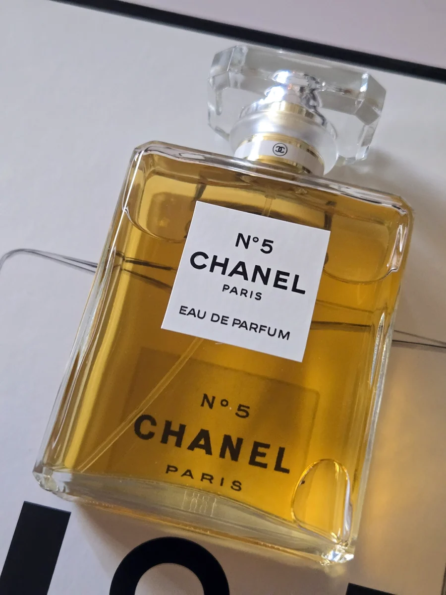 Chanel N°5 Eau de Parfum bottle resting on open pages of the Abrams book, "The Story of Chanel N°5."