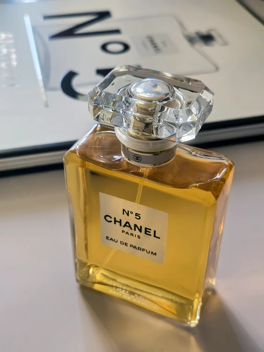 Chanel N°5 Eau de Parfum bottle resting on open pages of the Abrams book, "The Story of Chanel N°5."