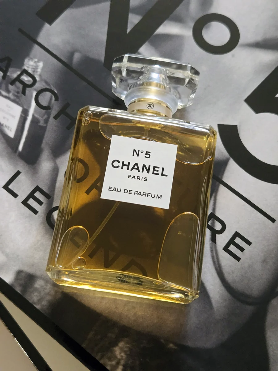 Chanel N°5 Eau de Parfum bottle resting on open pages of the Abrams book, "The Story of Chanel N°5."